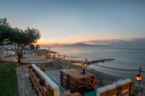a sunset over the ocean with a table and benches at Sea View Holiday Homes - Omega Estate Resorts in Kipseli