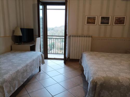 a hotel room with two beds and a balcony at La Casa Del Sole in Bomarzo