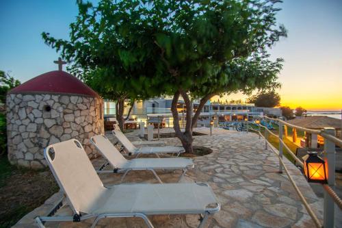 a group of lounge chairs and a tree and a building at Sea View Holiday Homes - Omega Estate Resorts in Kipseli