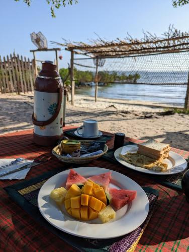 a table with two plates of food on a beach at Mawe Mawili in Tanga