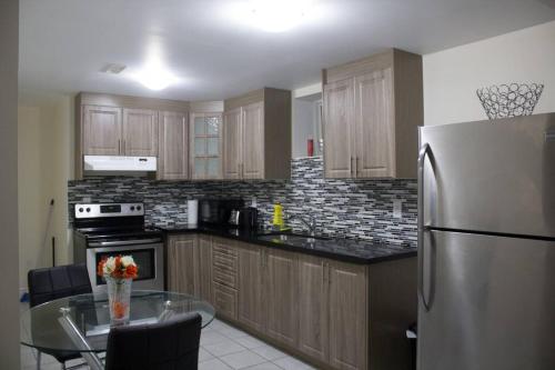 a kitchen with a stainless steel refrigerator and a table at Victoriaville Suite in Brampton