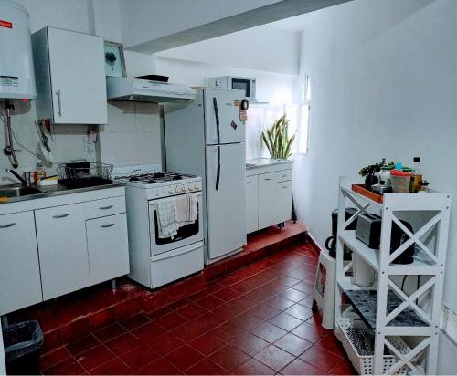 cocina con electrodomésticos blancos y suelo de baldosa roja en Mi lugarcito en La Rioja
