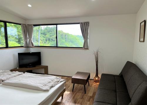 a bedroom with a bed and a couch and a television at Open House Sakurasakura - Kamakurayama - - Vacation STAY 14047 in Kamakura