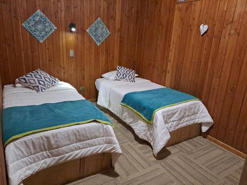 2 camas en una habitación con paredes de madera en Hostal Ruka Lodge, en Villarrica