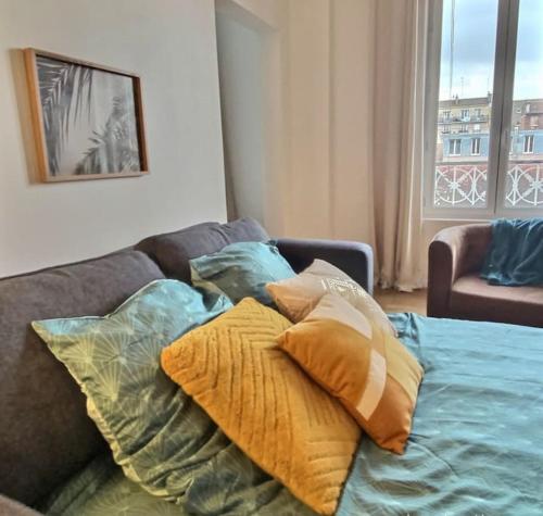 a pile of pillows on a couch in a living room at Appartement 2 pièces à quelques minutes de Paris in Le Pré-Saint-Gervais