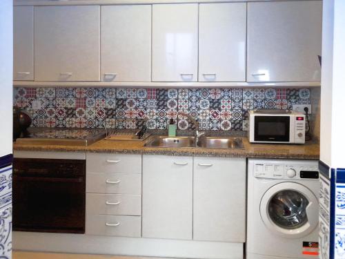a kitchen with a sink and a washing machine at Casa Miraflores in Seville
