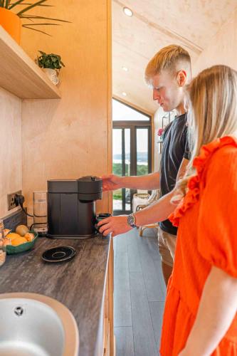 a man and a woman standing in a kitchen at Oaklane Glamping Cabins in Kenmare