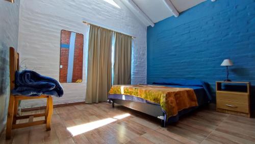 um quarto azul com uma cama e uma cadeira em Cabañas Laureano AJ em Cacheuta