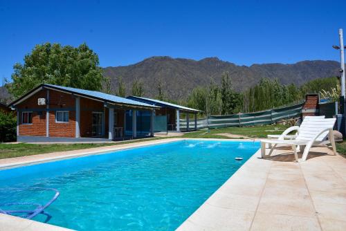 une piscine avec une chaise et une maison dans l'établissement Cabañas Laureano AJ, à Cacheuta