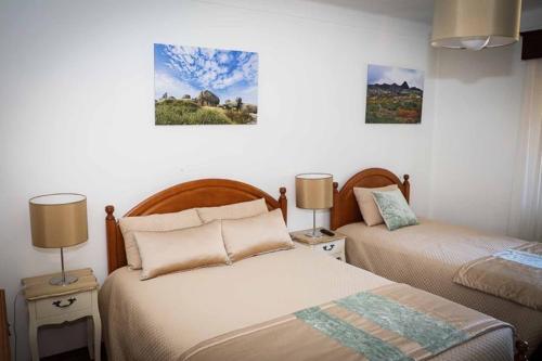duas camas num quarto com dois candeeiros e pinturas em Casa Fundo de Vila em Manteigas