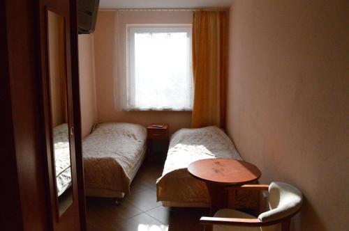 Cette chambre comprend 2 lits, une table et une fenêtre. dans l'établissement Ośrodek SUDETY, à Pokrzywna