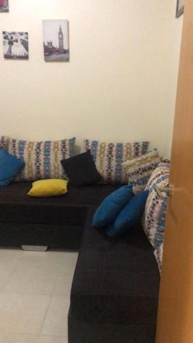 a couch with pillows on it in a living room at Petit appartement très chaleureux à 1 minute de marche du stade de Tanger(Ibn Batouta) in Tangier
