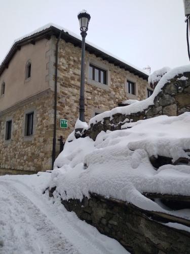 a snow covered street next to a building with a street light at La Posada de la Xana in Llanuces