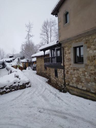 a house with snow on the ground next to a driveway at La Posada de la Xana in Llanuces