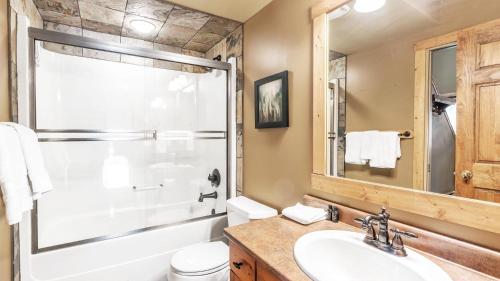 La salle de bains est pourvue d'un lavabo, d'une douche et de toilettes. dans l'établissement Forest Lane Hideaway - Luxurious Family Friendly Home with Private Hot Tub, à Big White