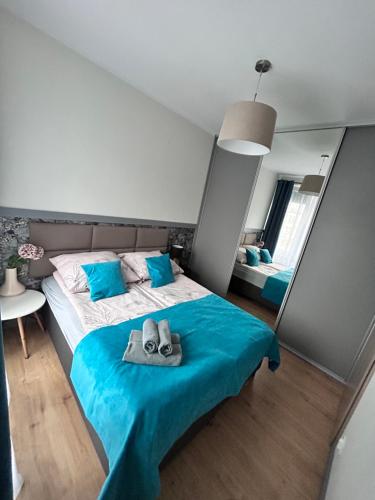 1 dormitorio con 1 cama con manta azul y zapatillas en Apartament Walczaka 43 MIEJSCE PARKINGOWE, en Gorzów Wielkopolski