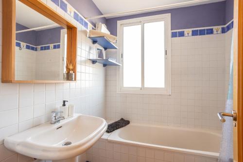 een badkamer met een wastafel, een bad en een raam bij Piso Peñoncillo in Torrox