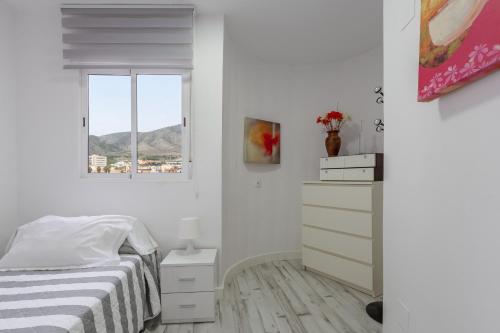 a white bedroom with a bed and a window at Apt Playa y Montaña in Torremolinos