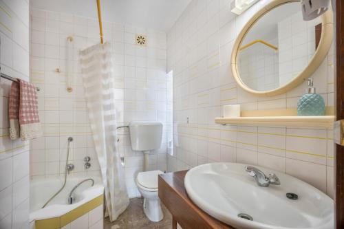 een badkamer met een wastafel, een toilet en een spiegel bij Apartamento Amarelo in Odeceixe