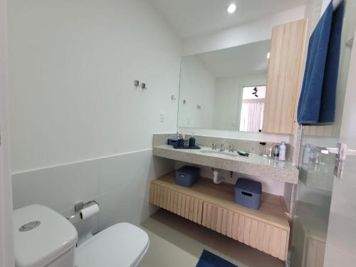W łazience znajduje się umywalka, toaleta i lustro. w obiekcie Vila Piemont Itaipava w mieście Itaipava
