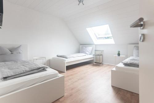 two beds in a room with white walls and wooden floors at Eindrucksvolles Gruppen– und Monteursloft in Edingen-Neckarhausen