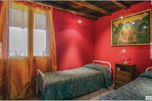 a red room with two beds and a window at la Casa sul Golfo in Trappeto