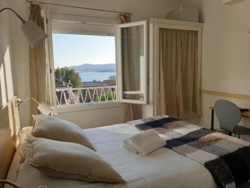 ein Schlafzimmer mit einem Bett und einem großen Fenster in der Unterkunft Hôtel La Petite Bohème in Le Lavandou