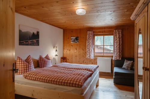 a bedroom with a bed and a couch and a window at Bergbauernhof Pabulariu in Boden