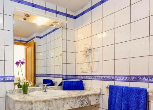 y baño con lavabo, espejo y toallas azules. en APARTAMENTO SA VARADERO 2D VISTA MARE LATERALE en Es Pujols