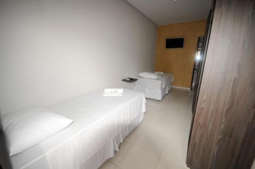 a white bedroom with two beds and a television at La Bella Hotel in Imperatriz