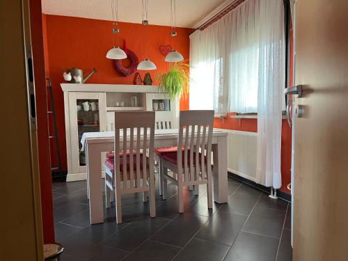 eine Küche mit orangefarbenen Wänden sowie einem Tisch und Stühlen in der Unterkunft Zentrale großzügige Dachterassen Whg am Stadtpark in 15 Min mit U-Bahn zur Messe in Nürnberg