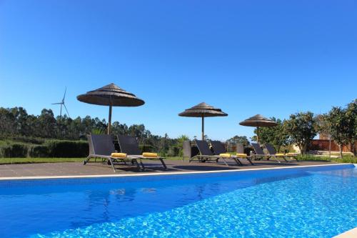 a group of chairs and umbrellas next to a swimming pool at Quinta das Alfambras in Aljezur