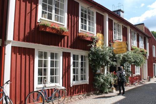 a person standing in front of a red and white building at Ferienhaus mit Kamin in Småland für 6 Personen in Järnforsen