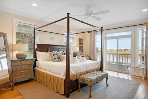 a bedroom with a canopy bed and a balcony at 616 E Erie Driftwood Marsh and River Views Private Pool in Folly Beach