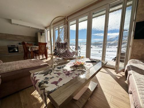 a living room with a hammock and a table with a view at Gorštak in Žabljak