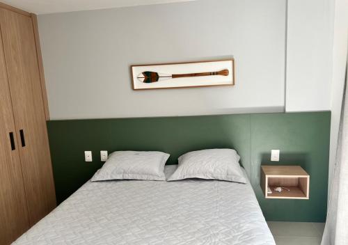 a bed with a green headboard with a bottle of wine on it at Itacimirim pé na areia 2Q in Itacimirim