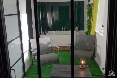 baño con bañera, 2 sillas y una vela en Suite Le Loft & Garden et Spa BY NANCYINTIMELOUNGE en Nancy