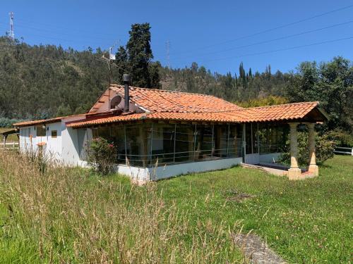 ein Haus mit einem orangenen Dach auf einem Feld in der Unterkunft Paipa de ensueño en casa Sochaloma in Paipa