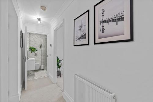 a white hallway with two pictures on the wall at Cosy Apartment in the heart of Southampton in Southampton