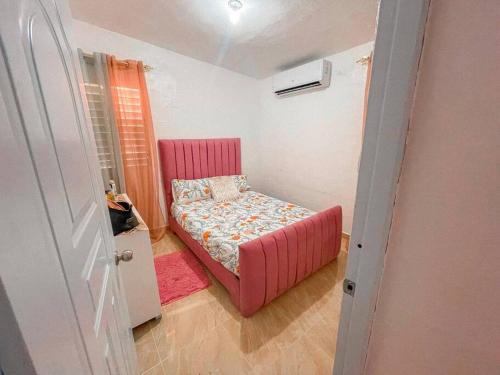 ein kleines Schlafzimmer mit einem rosa Bett in einem Zimmer in der Unterkunft Acogedora casa de 2 habitaciones in Villa Isabela