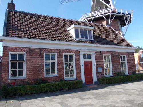 a red brick building with a windmill on top at B&B Het Molenhuisje Winschoten - met woonkamer & keuken in Winschoten