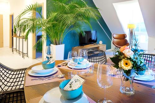 a dining room with a wooden table with glasses and flowers at HAMA Design Homes Lippstadt in Lippstadt