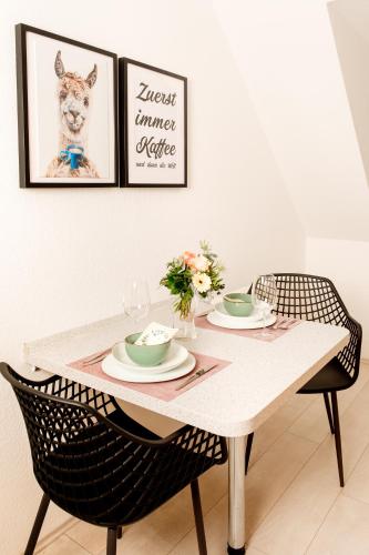 a dining room table with two chairs and a picture of a dog at HAMA Design Homes Lippstadt in Lippstadt