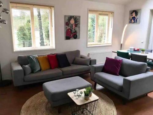 ein Wohnzimmer mit Sofa und Tisch in der Unterkunft Heerlijk huis in een prachtige bosrijke omgeving. in Putten