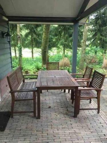 three wooden benches and a wooden table on a patio at Heerlijk huis in een prachtige bosrijke omgeving. in Putten