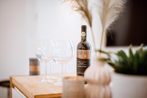 a bottle of wine and two wine glasses on a table at Da Alois - Alpine Premium Apartments in Gröbming
