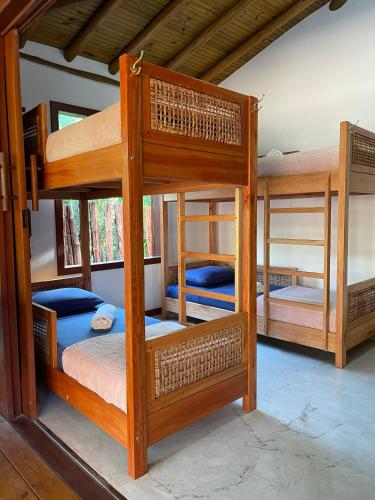 a room with three bunk beds in a house at Vulva Caraíva Hostel e Pousada para Mulheres in Caraíva