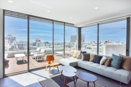 een woonkamer met een bank en grote ramen bij Michel Angelo by HolyGuest in Tel Aviv
