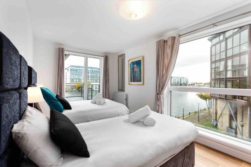 two beds in a room with a large window at Waterfront Luxury in Dublin