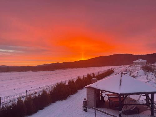 a snowy field with a gazebo and a sunset at Domek z Widokiem Na Bliżniaki in Chocznia